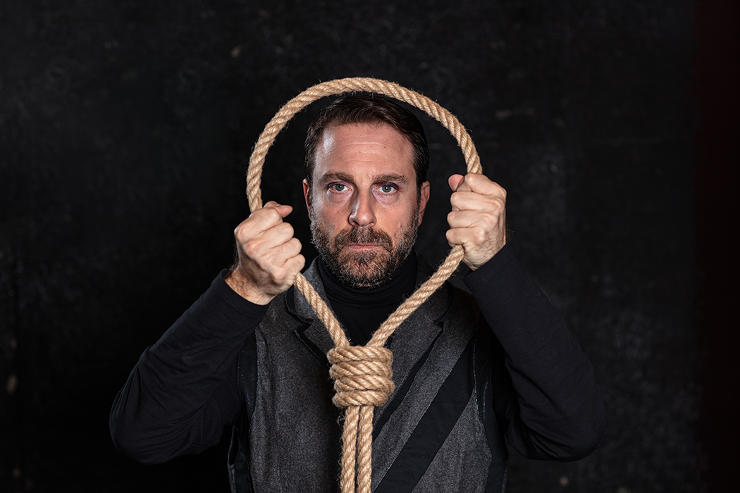 Portrait of an actor on the stage holding a rope